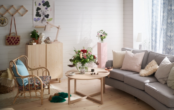 Ett vardagsrum med grå soffa, och möbler i trä, som tex stol, bord och byrå. Samt övrig dekoration