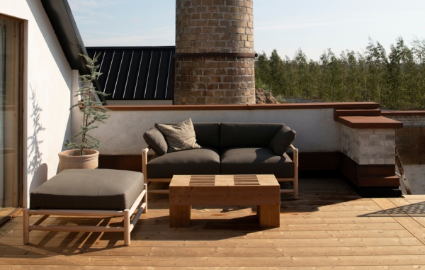 En takterass med trall och möbler i trä, en utsikt över grön skog