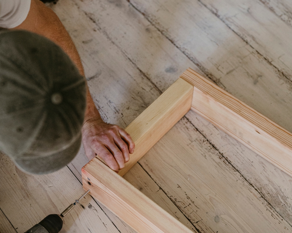 En man skruvar ihop reglar till en ram