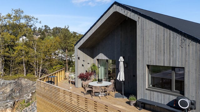Enebolig med Værbitt kledning omgitt av skog og fjell