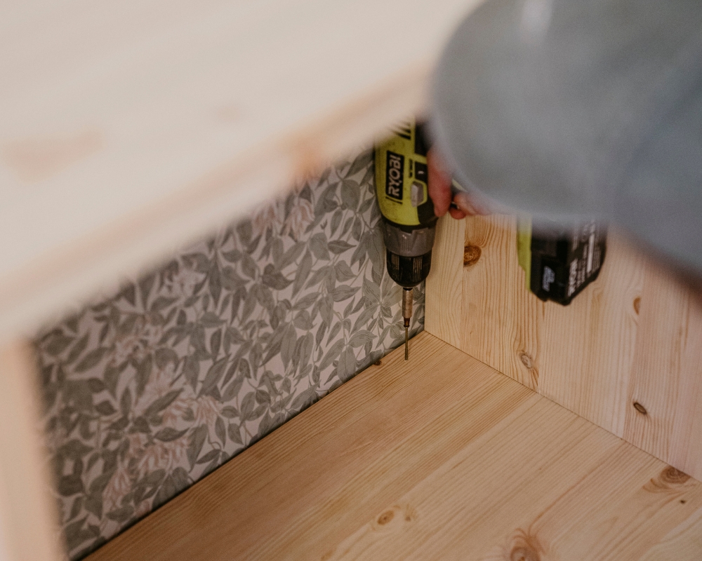 En trähylla skruvas fast i en ram