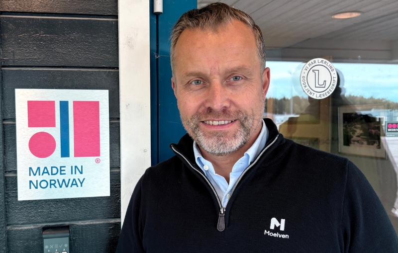 Ansatt fra Moelven Byggmodul står ved siden av skiltet Made in Norway.