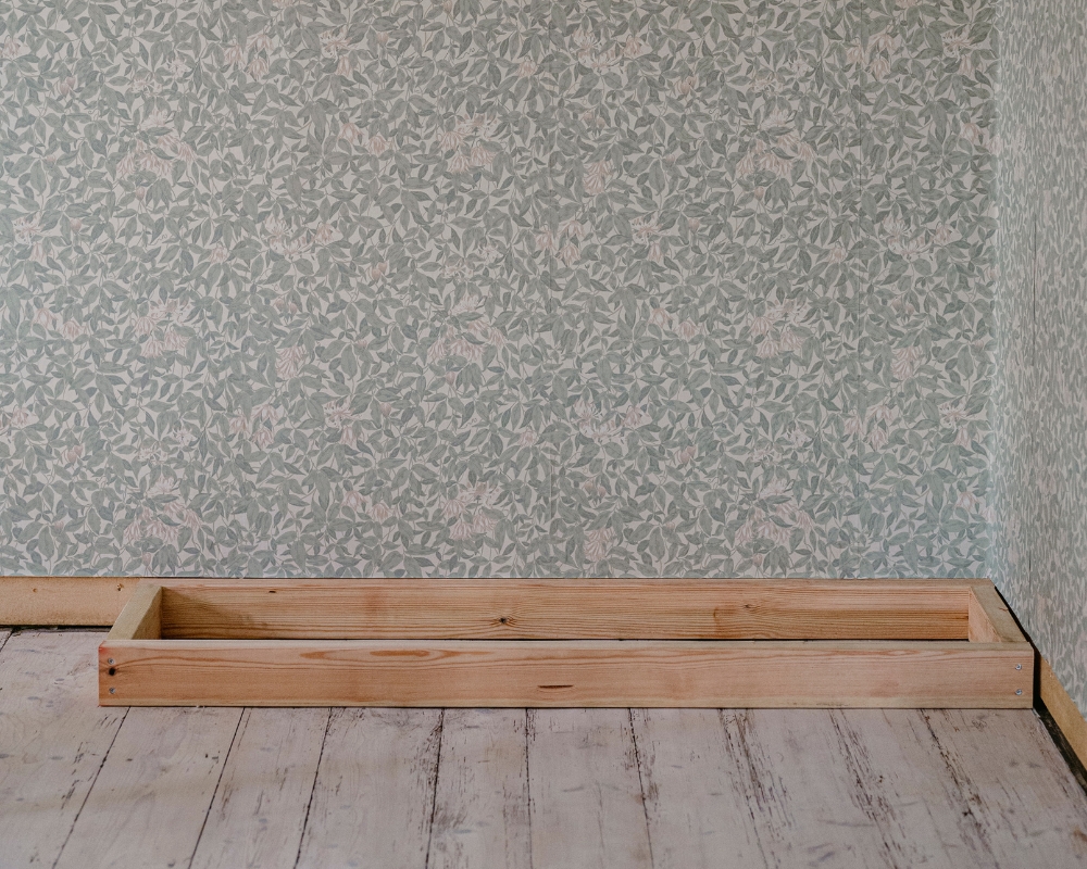 En träram placerad i ett hörn av ett rum