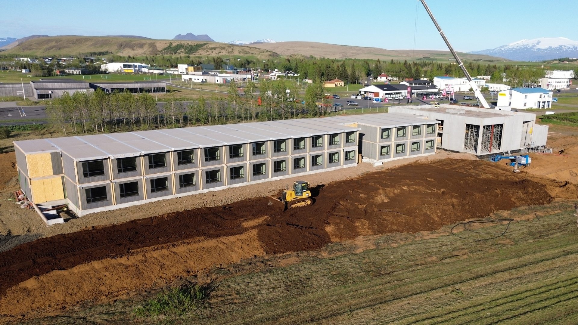 Loftmynd af tveggja hæða hótelbyggingu í smíðum á opnu svæði.