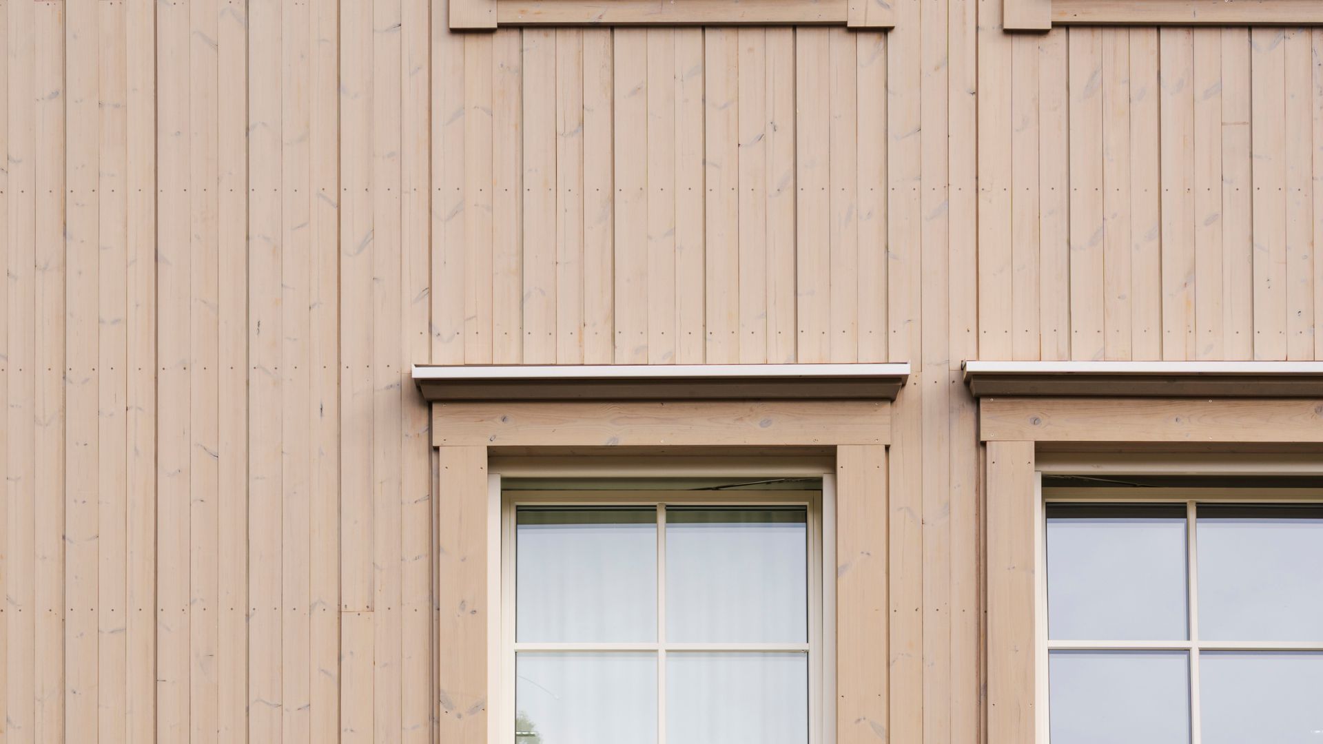 ljus beige fasad i olika profiler med fönster med spröjs