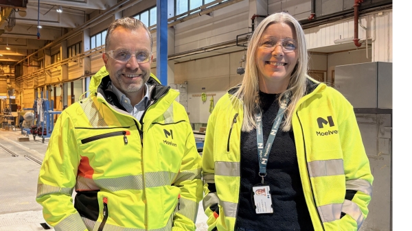 To personer i synlighetsjakker i et fabrikklokale.