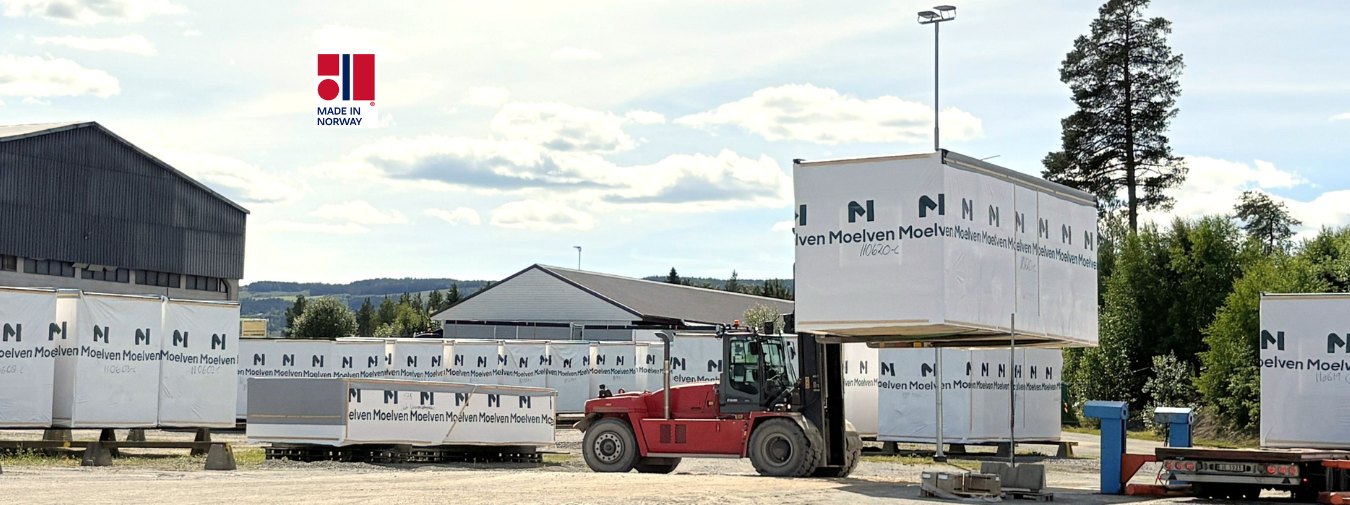 Gaffeltruck med en byggmodul i Moelven-profilert emballasje på Moelven Byggmodul sitt område.