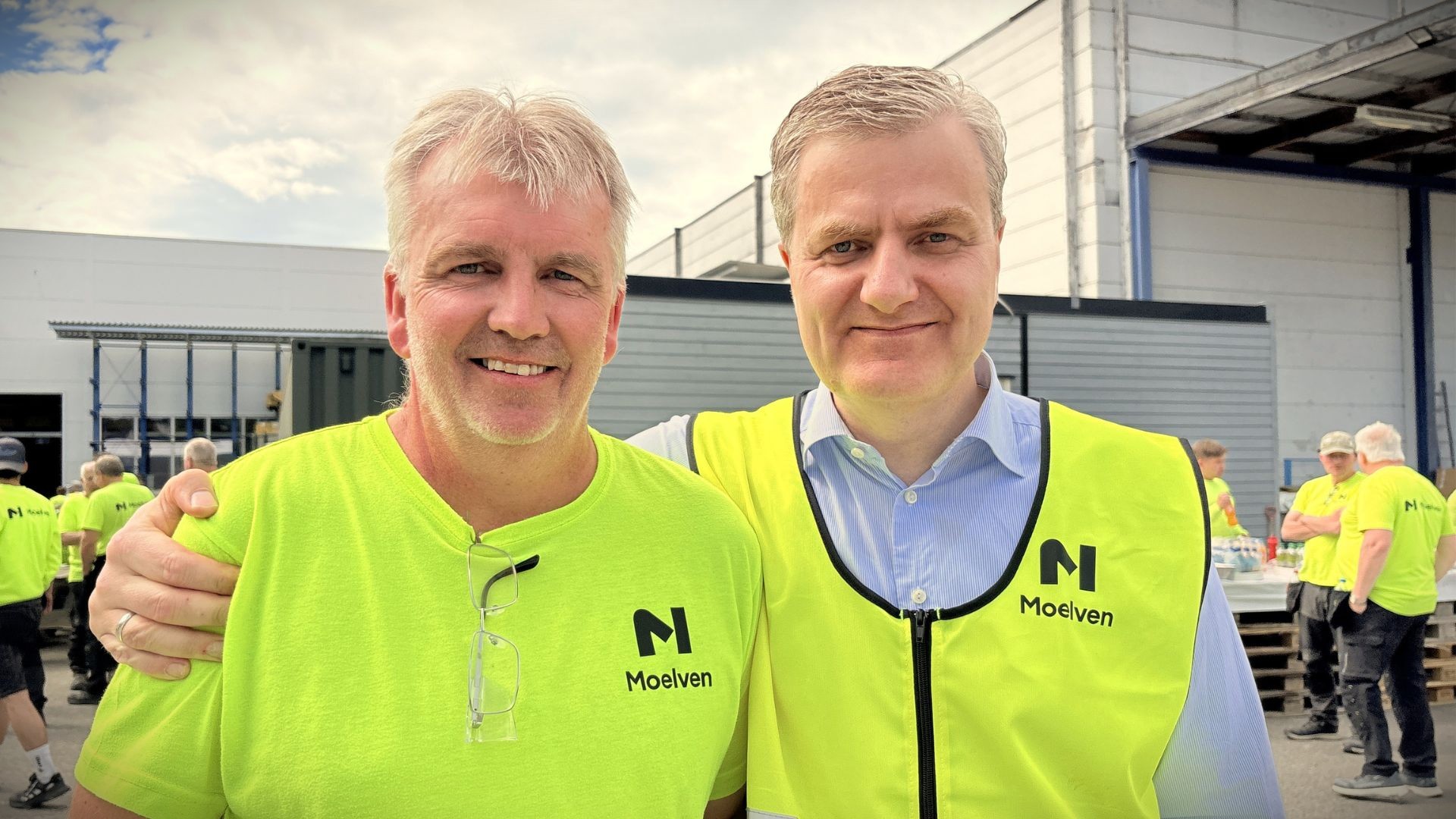 To menn ikledd synlighetstøy utenfor fabrikken hos Moelven Byggmodul.