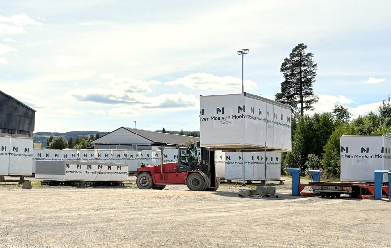 Gaffeltruck løfter en prefabrikkert byggmodul med Moelven-logo på emballasjen ved Moelven Byggmodul sitt område.