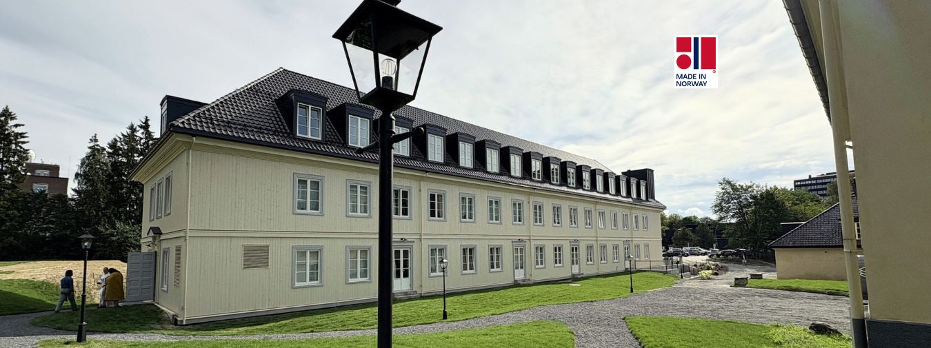 Fasaden av Blindern Studenterhjem med en lysstolpe i front. Gult bygg med svart tak.