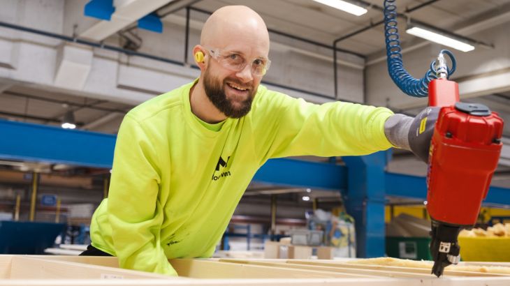 En smilende mand i fabrikken hos Moelven Byggmodul AS.