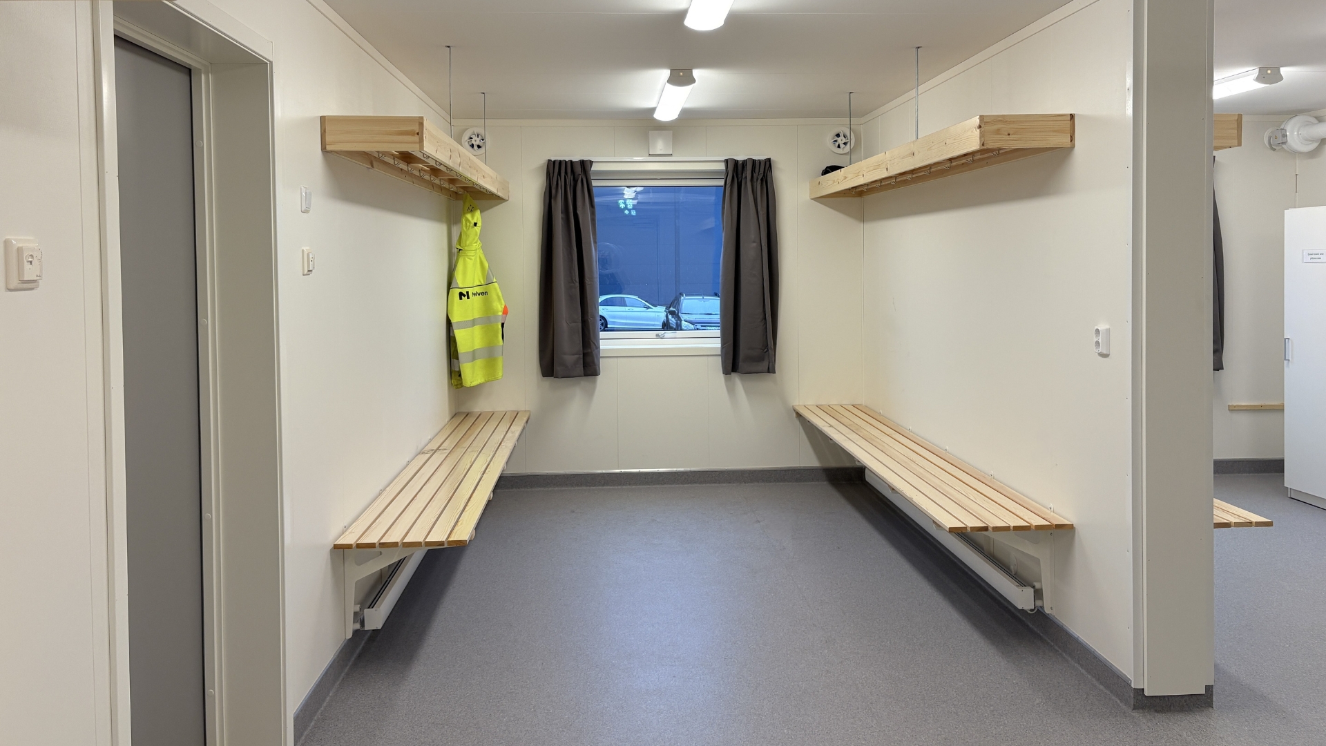 Indvendigt omklædningsrum i boligpavillon med bænke, knagerækker og god plads til arbejderne
