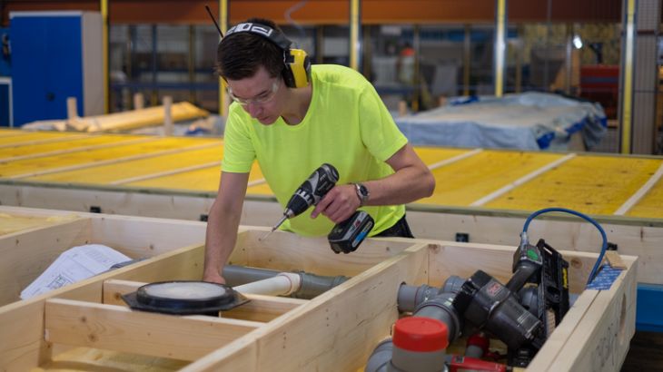 A factory worker produces a floor element.
