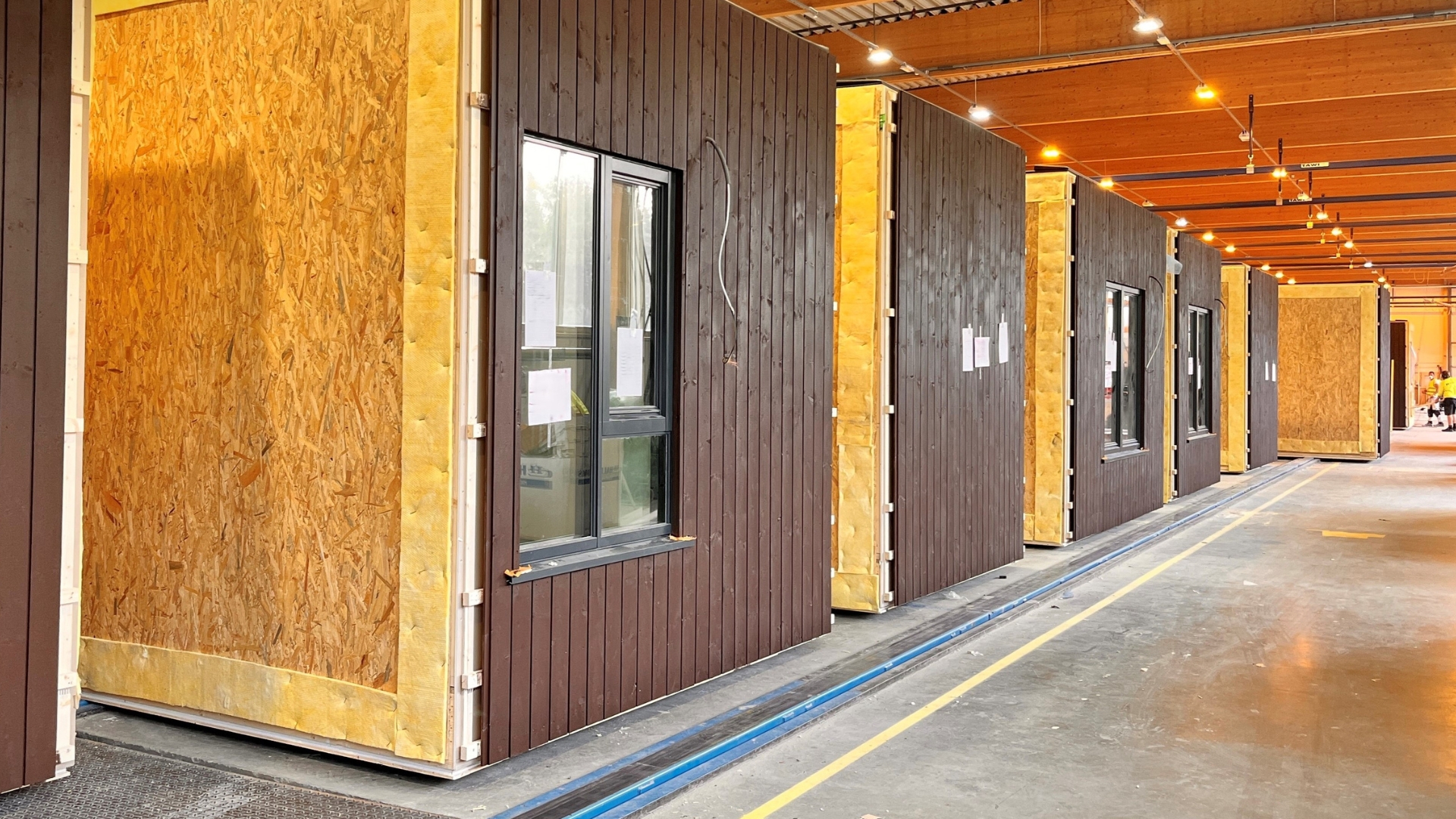 Brúnlituð viðareining stendur í röð hver á eftir annarri eftir endilangri verksmiðjunni.