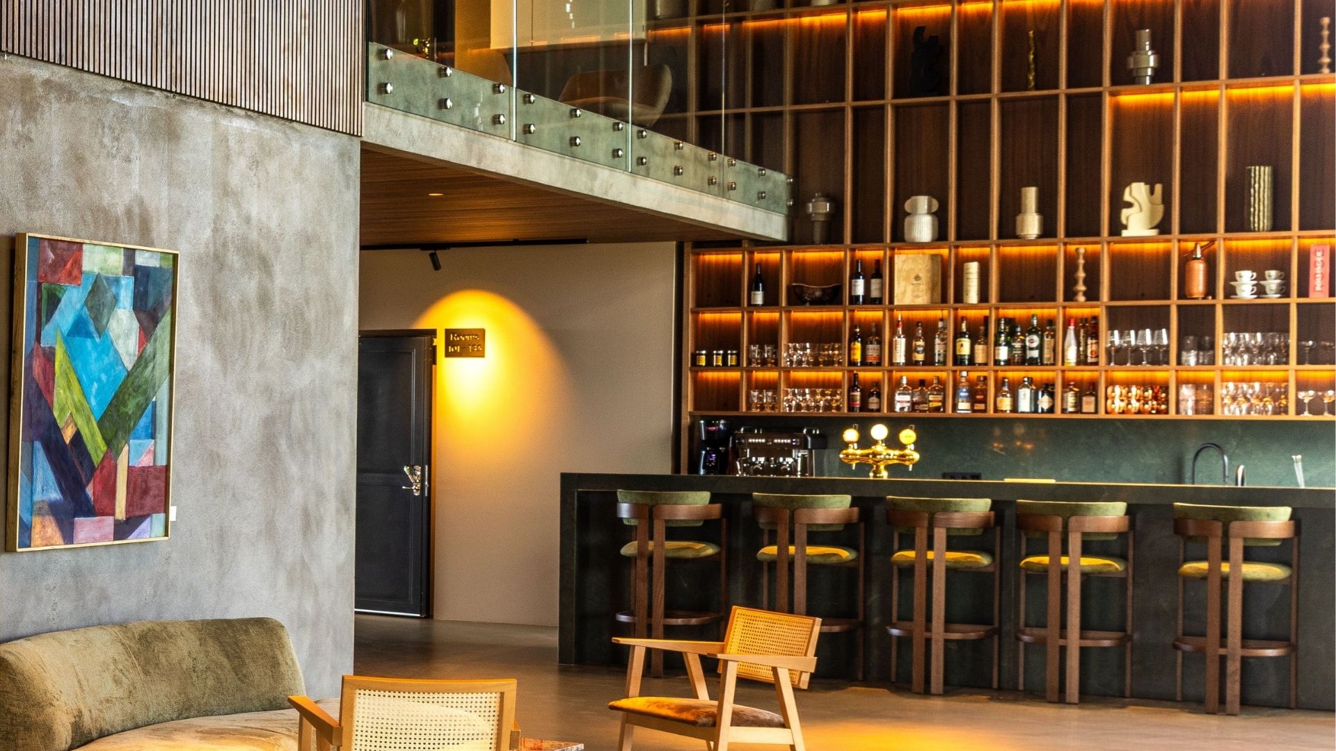 Barssvæði á Hotel Loa með barborði, barstólum og upplýstum hillum fyrir drykki.