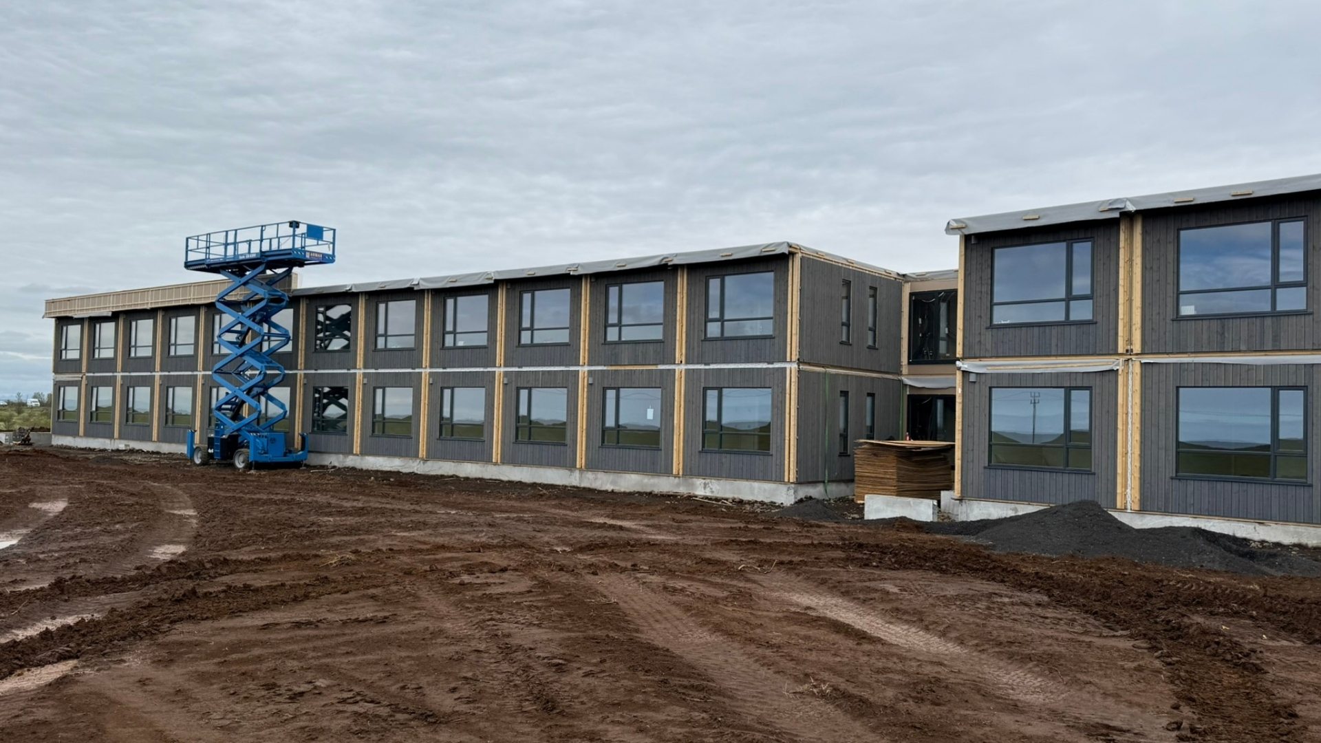 Tveggja hæða hótelbygging í smíðum úr einingum, með vinnupöllum og byggingarefni fyrir framan.