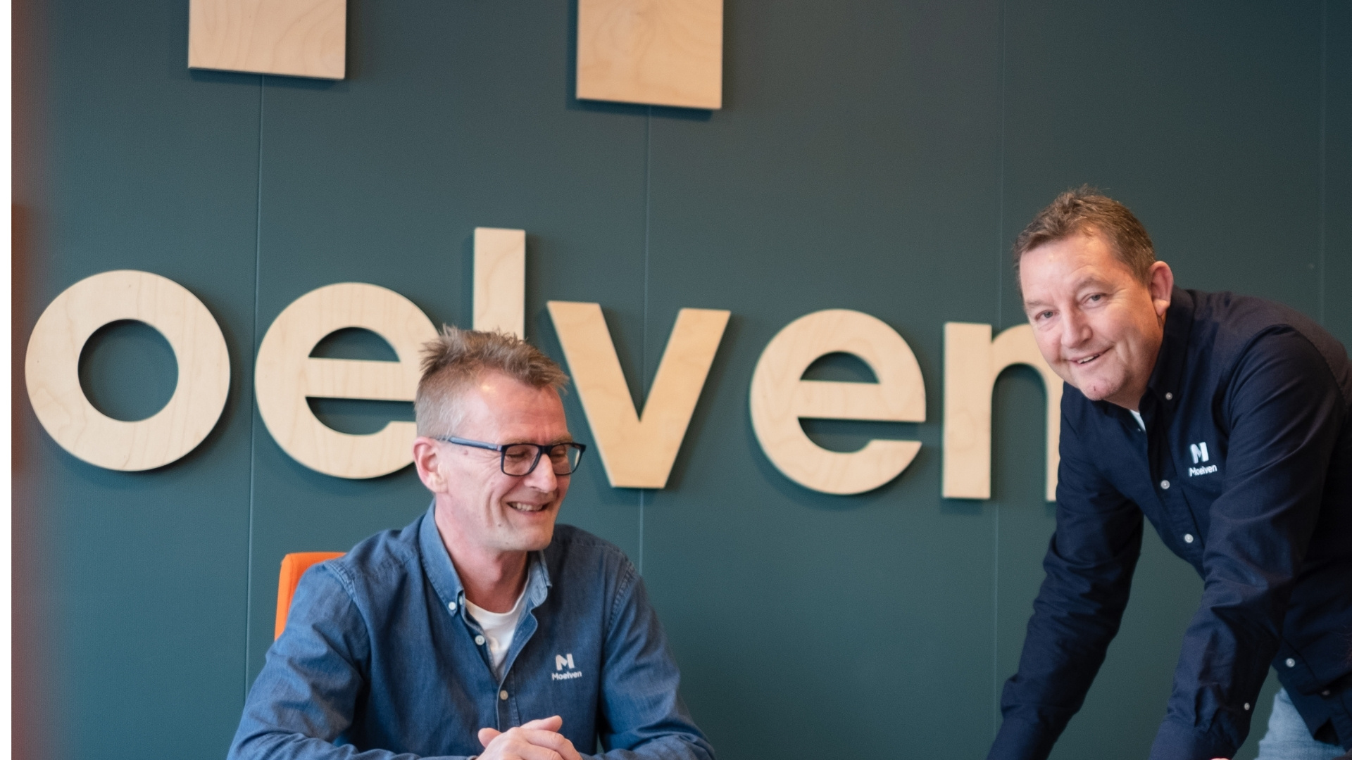 Двоє усміхнених чоловіків за столом.