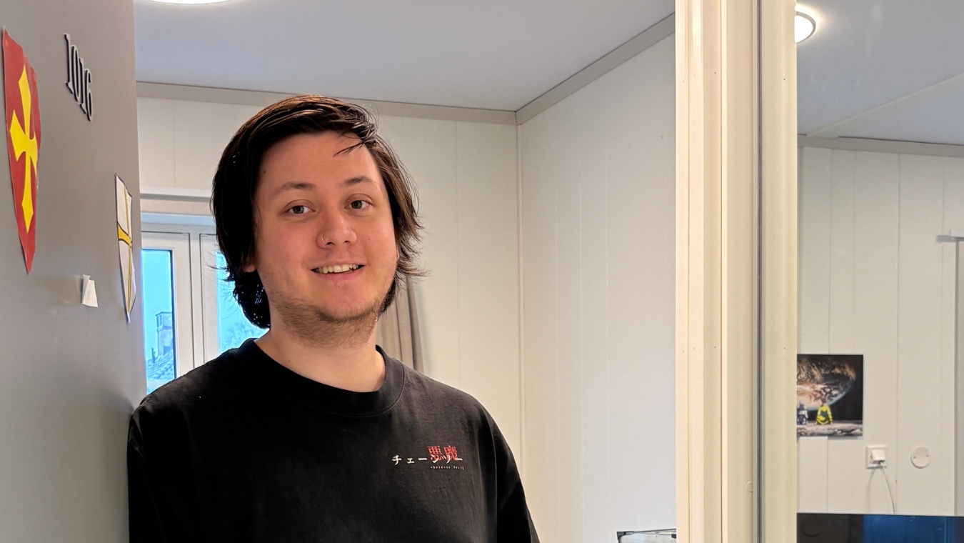 Smilende person som lener seg inn til en åpen dør inn til hybelen.