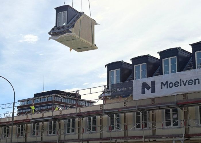 En byggmodul som henger i en heisekran.