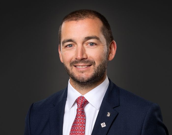 Portrettfoto av mann i dress og slips som smiler.