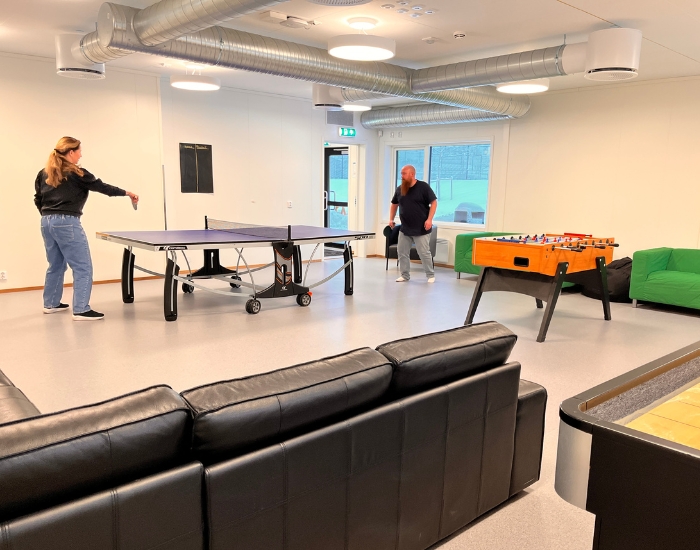 To personer som spiller bordtennis i et stort aktivitetsrom.