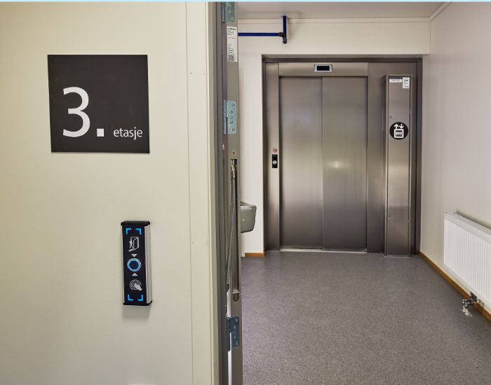 Et skilt som forteller at man er i 3. etasje og perspektiv inn mot heisdør.