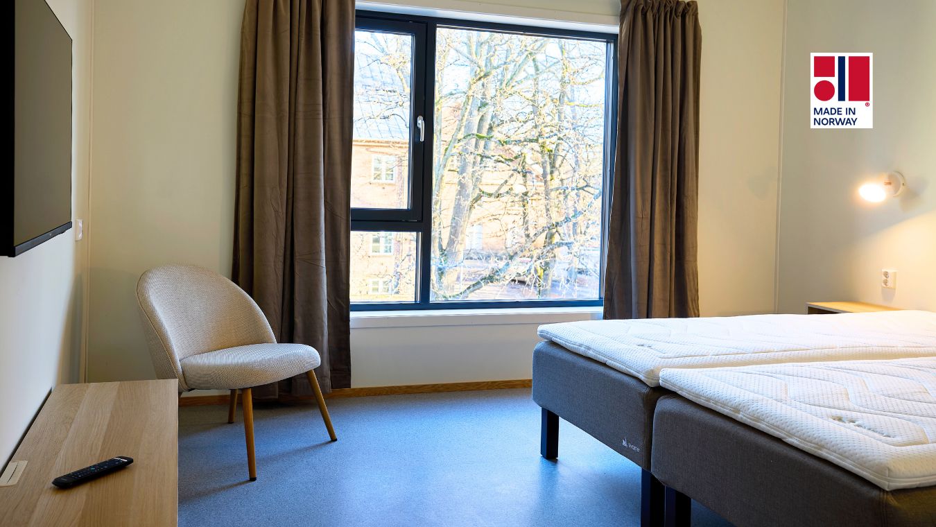 Hotellrom med stort vindu, dobbeltseng og møbler.