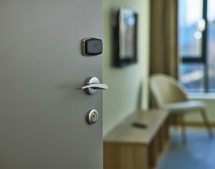 Nærbilde av en grå dør som står på gløtt. Skimter et rom innenfor.