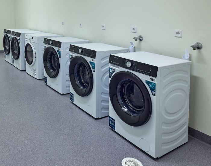 Vaskemaskiner og tørketromler som står på rekke langs en vegg.