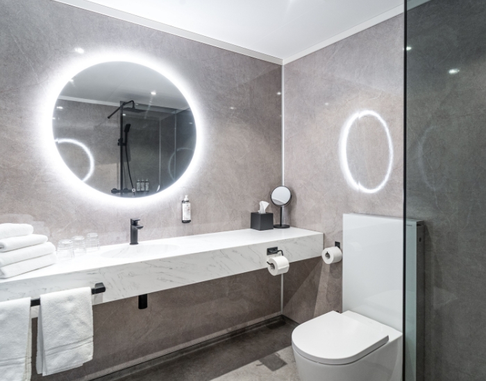 Moderne bad i delikat, grå og hvit utførelse. Lys rundt speil.