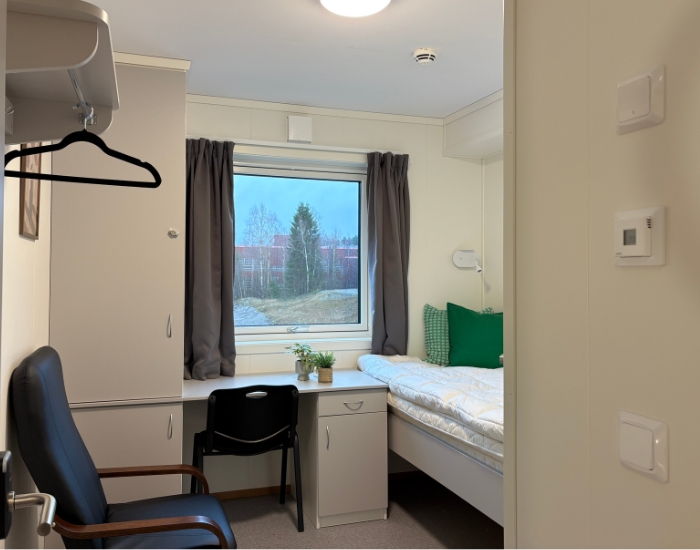 Komfortabel hybel i boligrigg med stort vindu, skrivebord, seng og oppbevaringsplass.