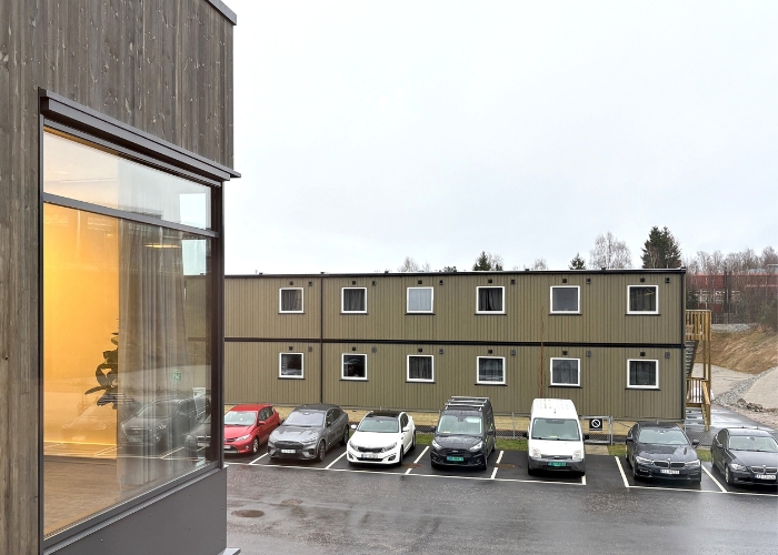 Toetasjes modulbygg med parkeringsplass i forgrunnen.