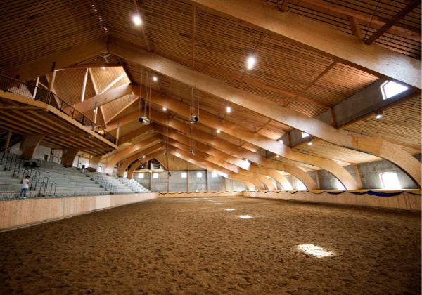 Ridhus i mörkt trä med lampor i taket, person på lektaren