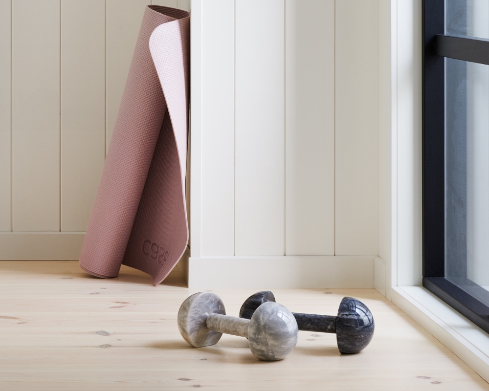 hemmagym med vit träpanel och ljust trägolv, hantlar och yogamatta