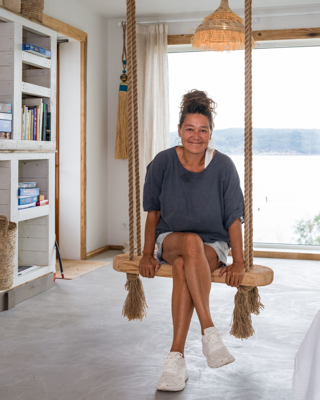 Sonja Lee sitter på en inomhusgunga av trä i ett rum med träpanelen Trend Slät