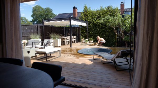Utsikt över en altan av tryckimpregnerad furu där en pojke hoppar i en pool