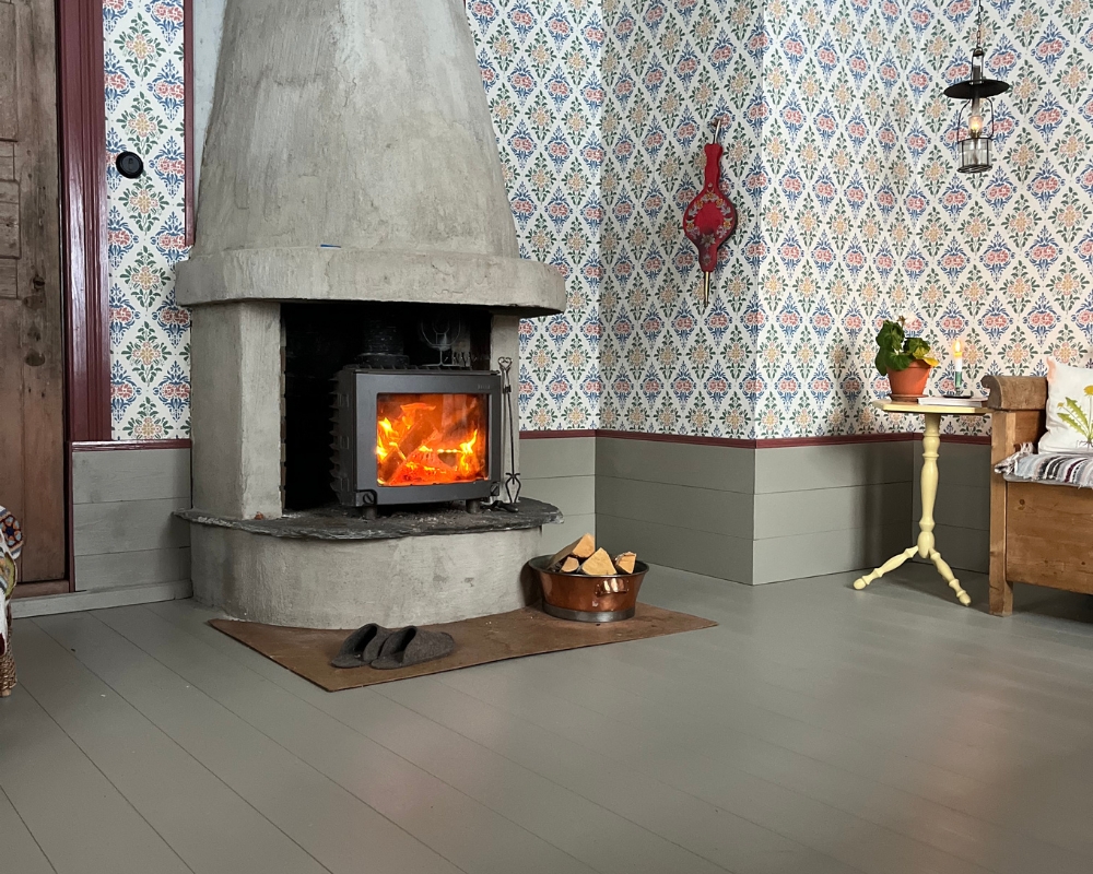 En kamin som eldas i och ett gråmålat trägolv