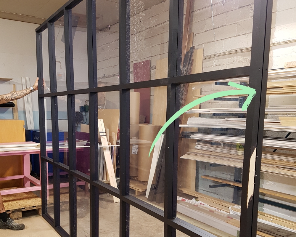 En skiljevägg i svart med plexiglas som visar att det är en glipa mellan ramarna