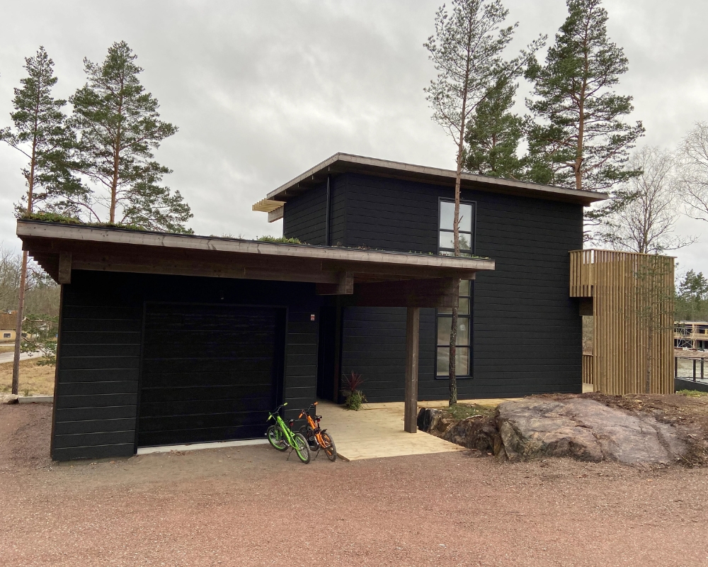 Ett hus med svart limträpanel och två cyklar