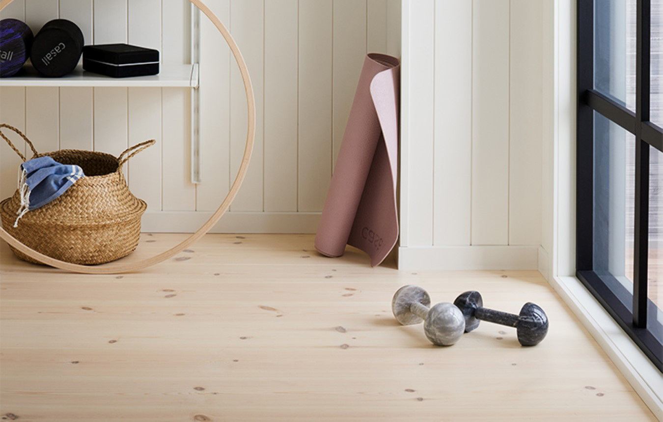 Hemmagym med ljust trägolv och vit träpanel