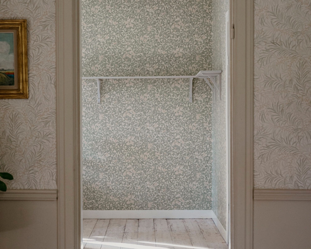 Öppning av en dörr, in till ett tomt rum med trägolv och tapet