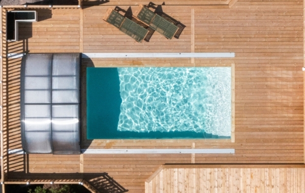 Flygbild över en pool med trädäck runt omkring