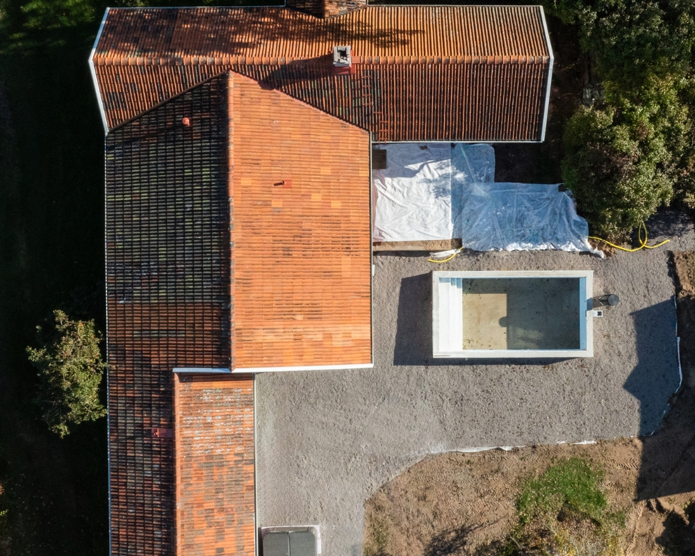 Foto taget ovanifrån ett hus med rött tegeltak, samt grunden för en pool