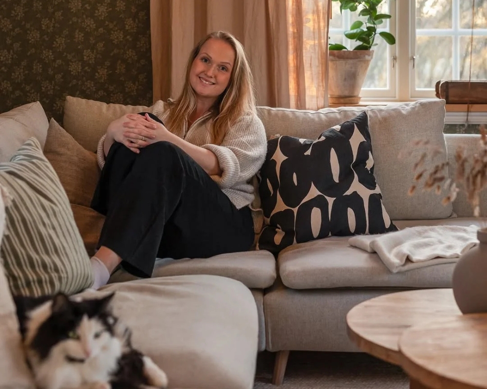 en tjej och en katt sitter i en grå soffa