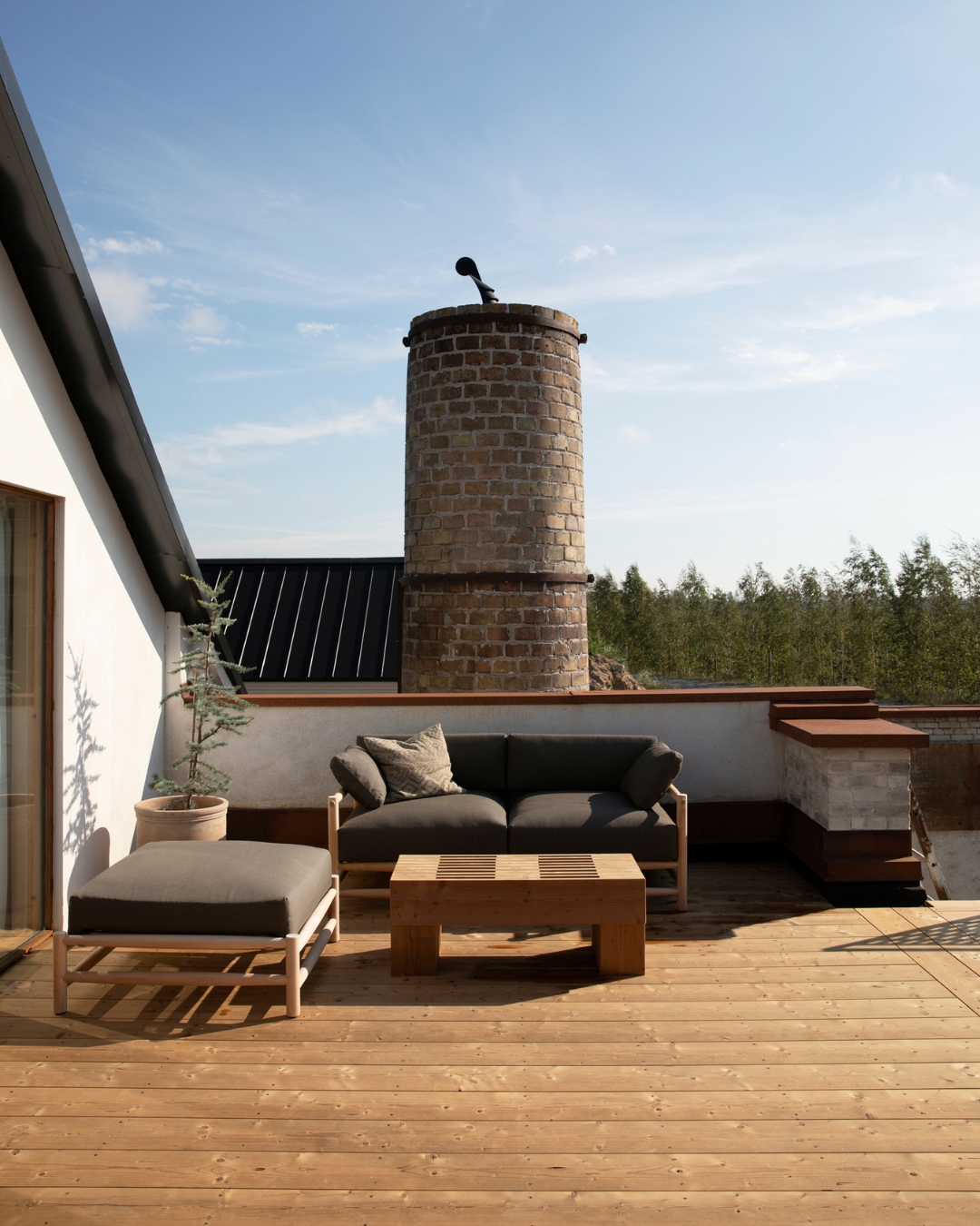 Terrass av TermoGran med möbler och ett murat torn i bakgrunden