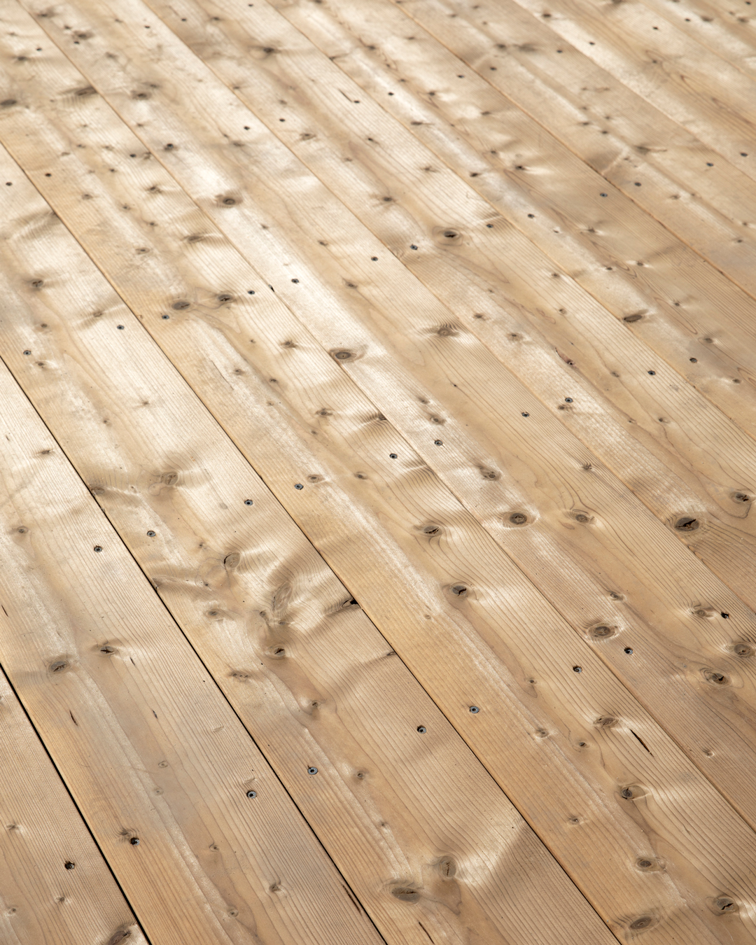 Närbild av en nylagd trätrall med synliga skruvar och naturlig ådring.