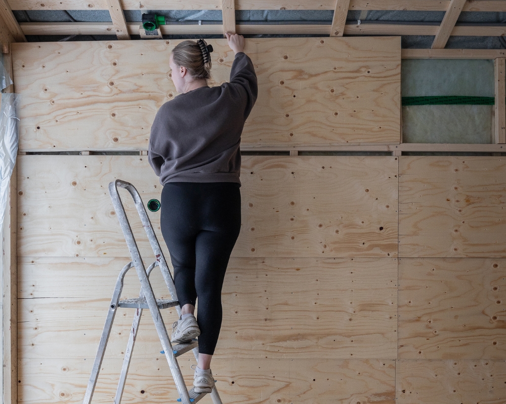 En kvinna som monterar konstruktionsplywood till  innerväggarna