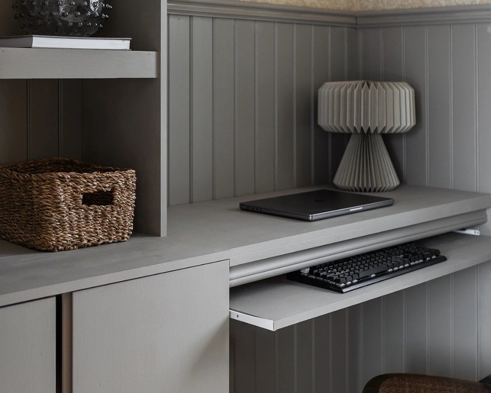 Platsbyggt skrivbord i trä,  målat i grått. En dator och tangentbord
