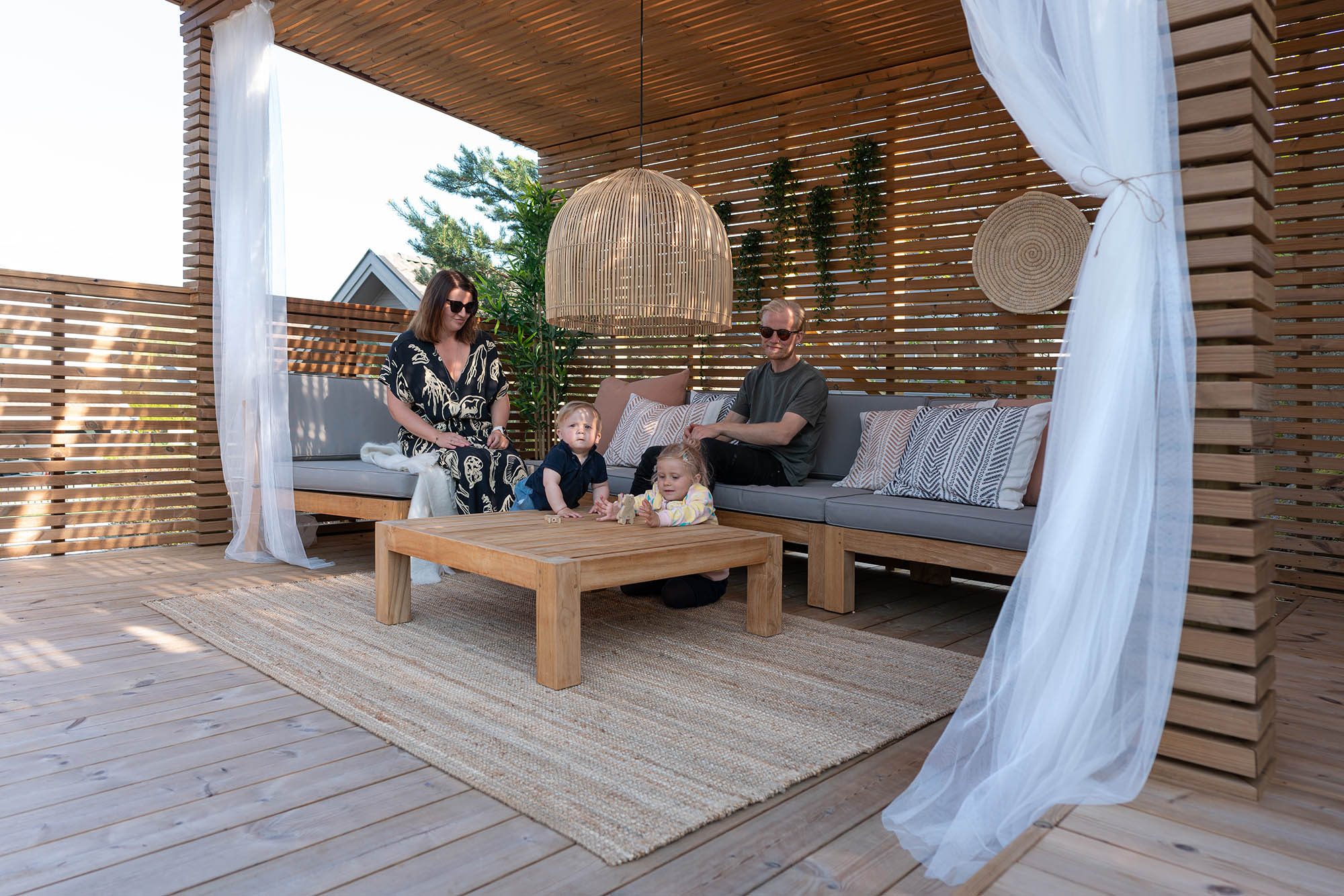 Familj sitter i soffan på en altan