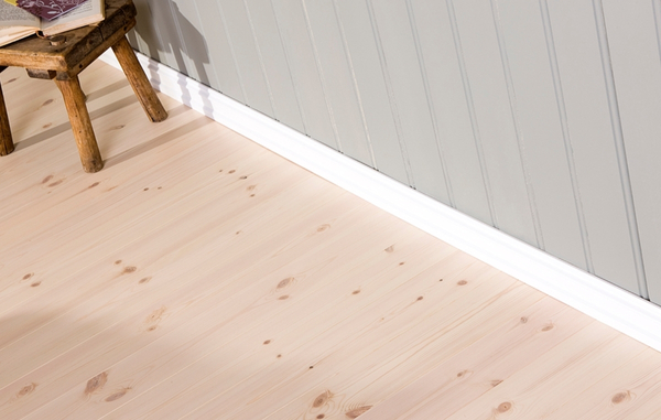 Ett ljust trägolv och en grå träpanel, med vita lister, samt en träpall